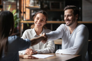 Young couple meeting with real estate agent and shaking hands