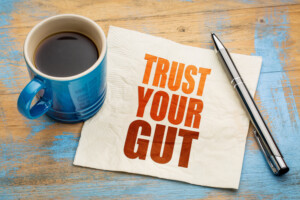 Coffee mug and pen next to paper that says "trust your gut"