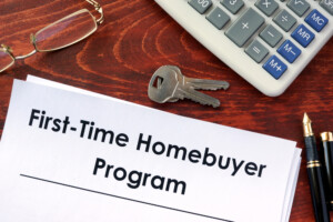 Paper with heading first-time homebuyer program next to keys and calculator