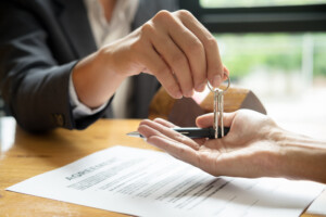 Real estate agent handing keys to client over signed contract