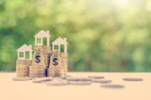 3 models of houses on stacks of coins of various heights