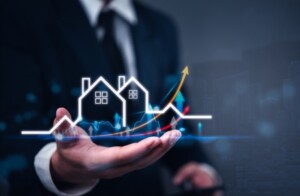 Hand holding visualization of houses with upward trending arrows