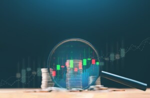 Stacks of coins and magnifying glass with trends chart